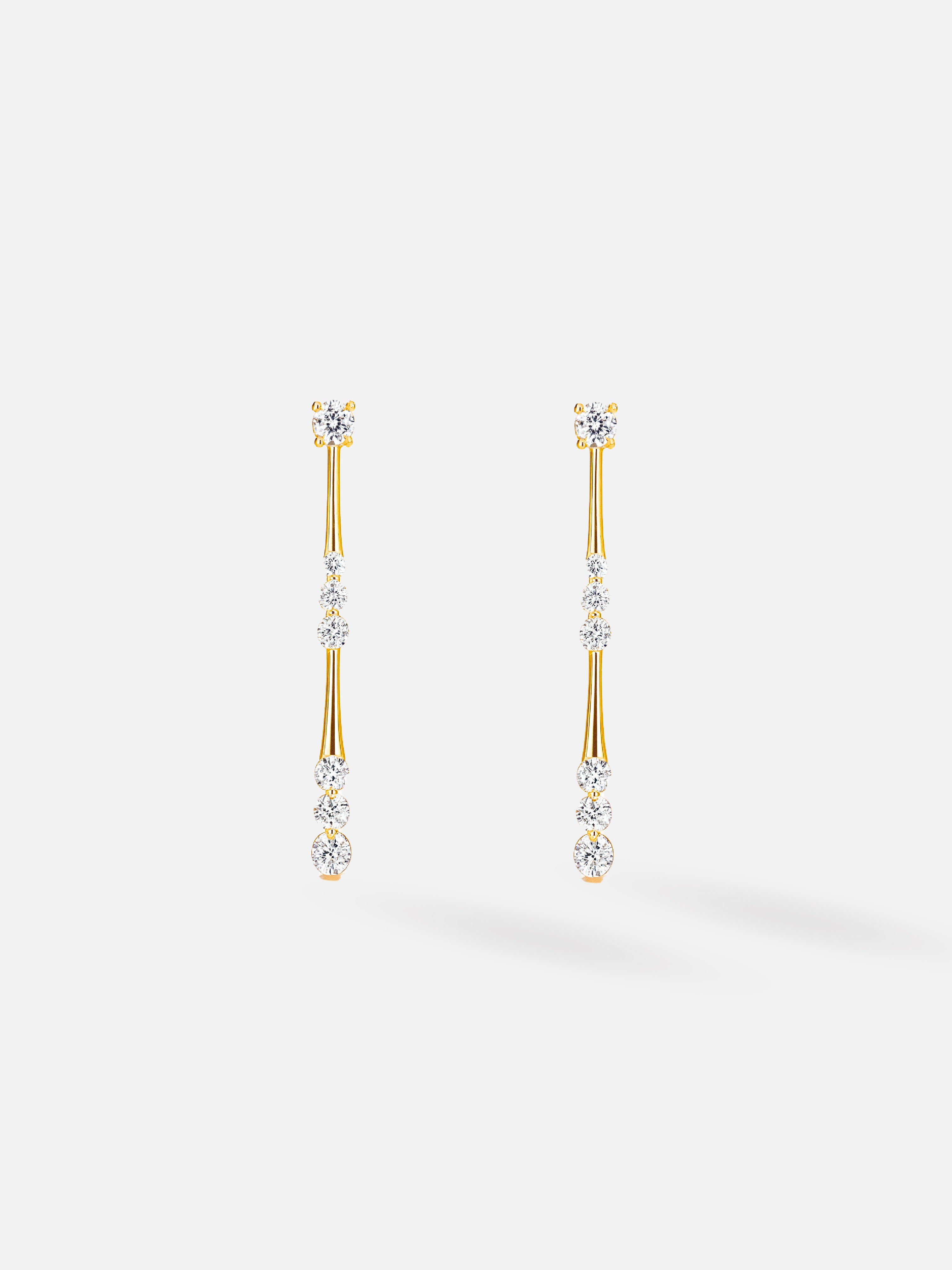 Gold earrings with clear stones on a white background
